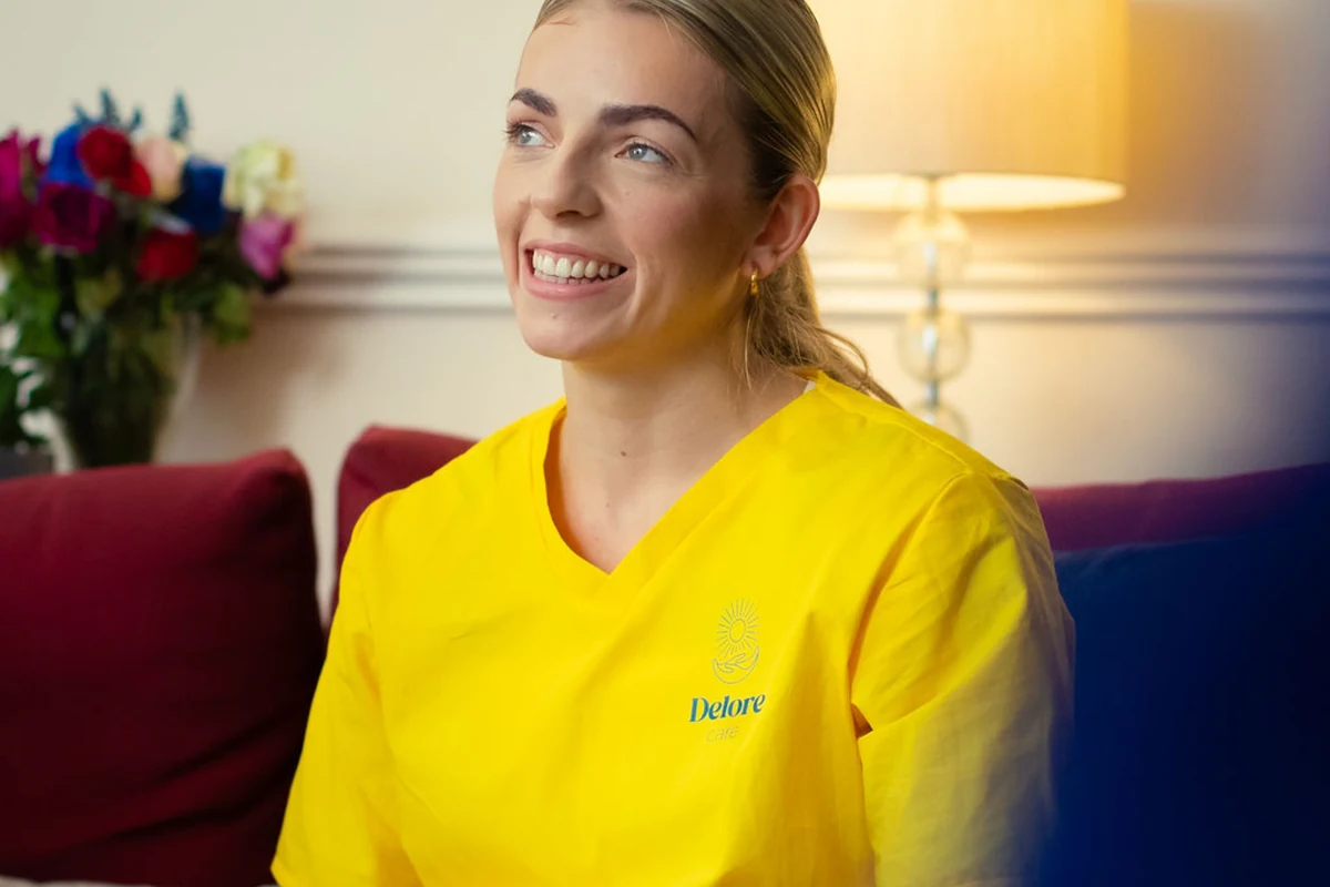 A Delore Care professional wearing a yellow uniform